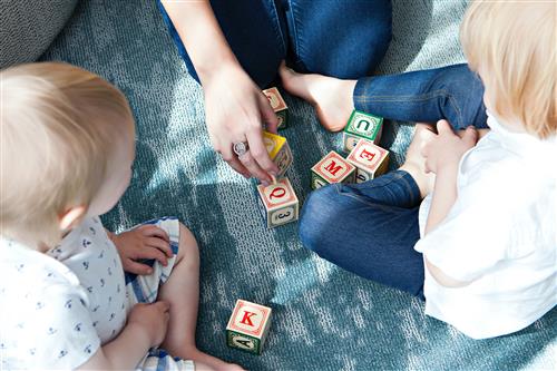 parent playing with letter blocks and young children