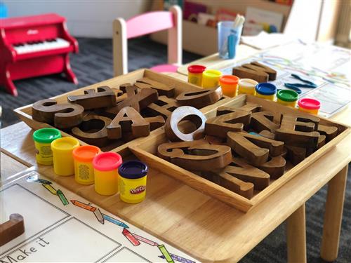 wooden letter blocks and playdough on a preschool table